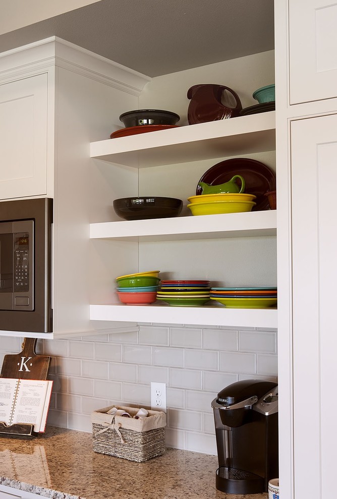 Example of a l-shaped kitchen design with stainless steel appliances and an island