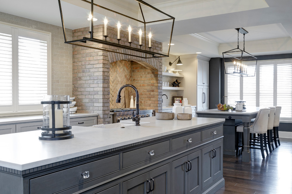 Traditional galley eat-in kitchen in Columbus with a farmhouse sink, recessed-panel cabinets, blue cabinets, brick splashback, panelled appliances, dark hardwood floors and multiple islands.