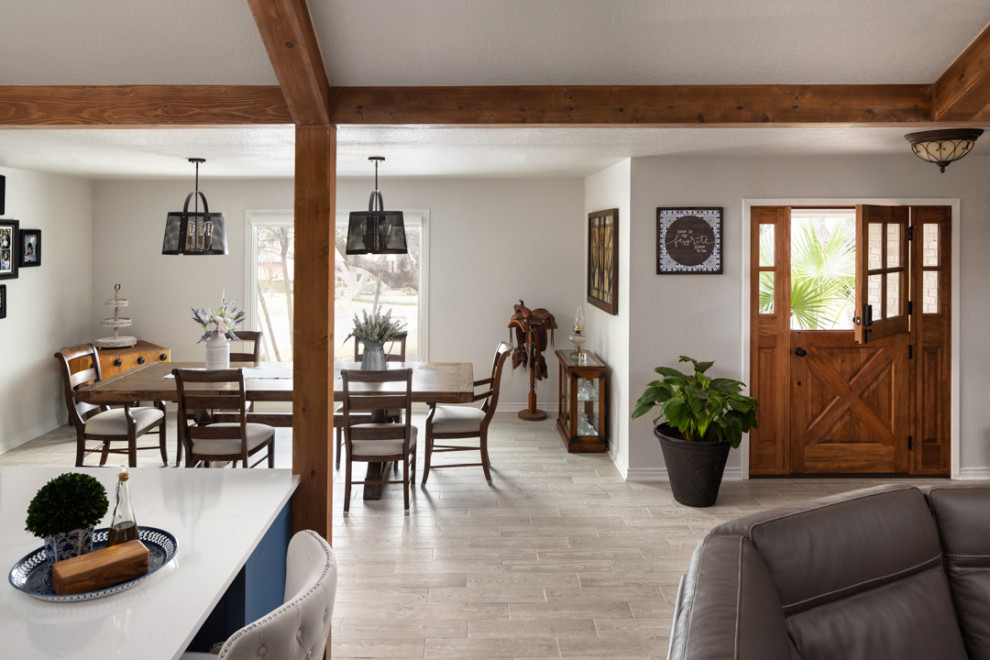 Idée de décoration pour une salle à manger ouverte sur le salon champêtre de taille moyenne avec un mur blanc, un sol en carrelage de céramique, aucune cheminée, un sol beige et poutres apparentes.