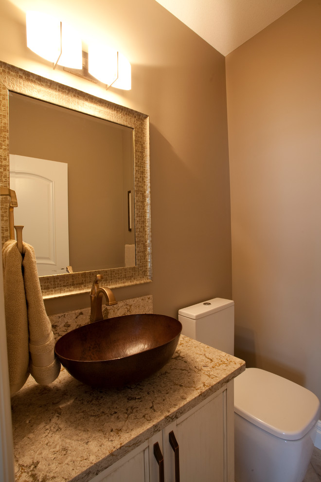 Photo of a transitional powder room in Calgary with a vessel sink, furniture-like cabinets, distressed cabinets, engineered quartz benchtops, a one-piece toilet, beige tile, beige walls and ceramic floors.