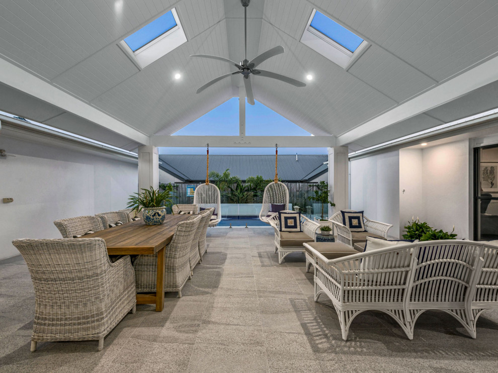 Large beach style side yard patio in Brisbane with concrete slab and a roof extension.