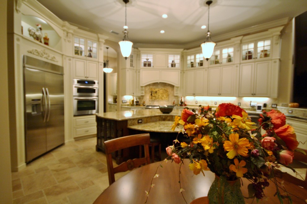 Inspiration for a large transitional u-shaped travertine floor eat-in kitchen remodel in Tampa with raised-panel cabinets, white cabinets, granite countertops, beige backsplash, stainless steel appliances and an island