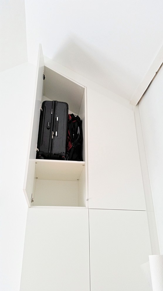 Photo of a mid-sized contemporary gender-neutral built-in wardrobe in Lille with beaded inset cabinets, white cabinets and light hardwood floors.