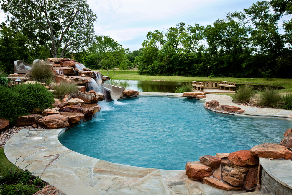 Inspiration for a large traditional backyard custom-shaped lap pool in Houston with a water slide and natural stone pavers.