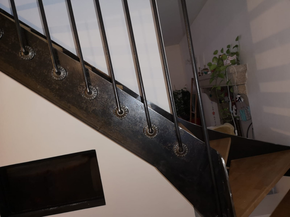 На фото: большая изогнутая лестница в стиле лофт с деревянными ступенями и перилами из смешанных материалов