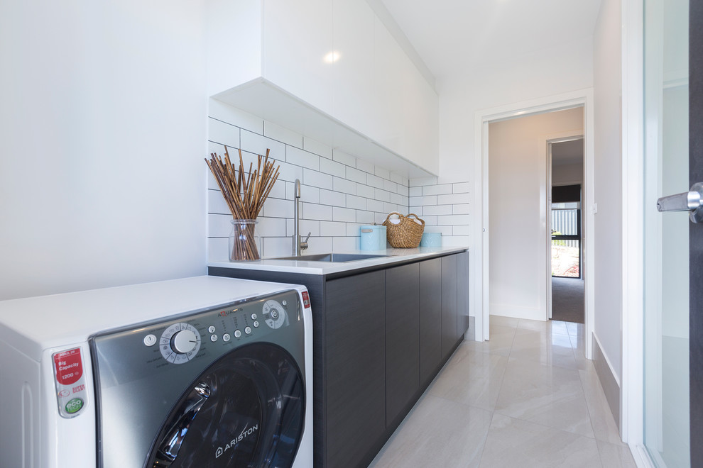 Mid-sized contemporary single-wall dedicated laundry room in Canberra - Queanbeyan with a drop-in sink, brown cabinets, granite benchtops, white walls, ceramic floors, beige floor and an integrated washer and dryer.