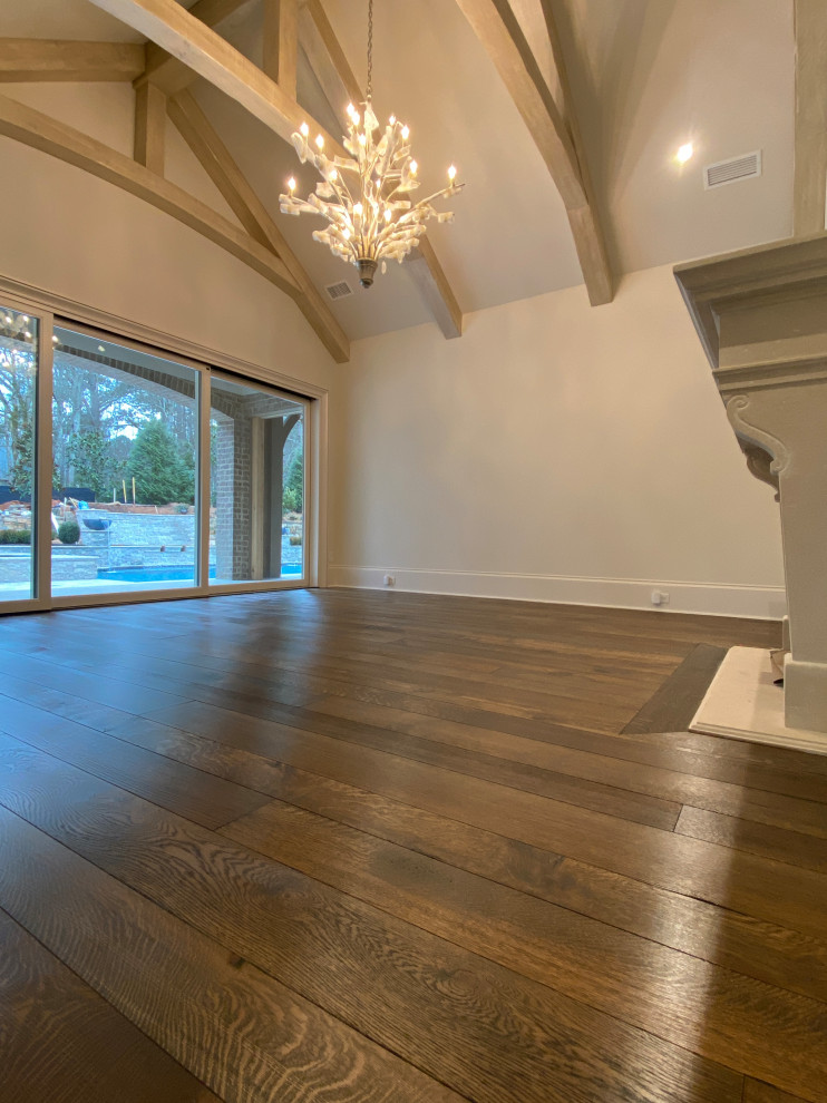 Inspiration for a large master bedroom in Atlanta with white walls, dark hardwood floors, a standard fireplace, a concrete fireplace surround, brown floor and exposed beam.