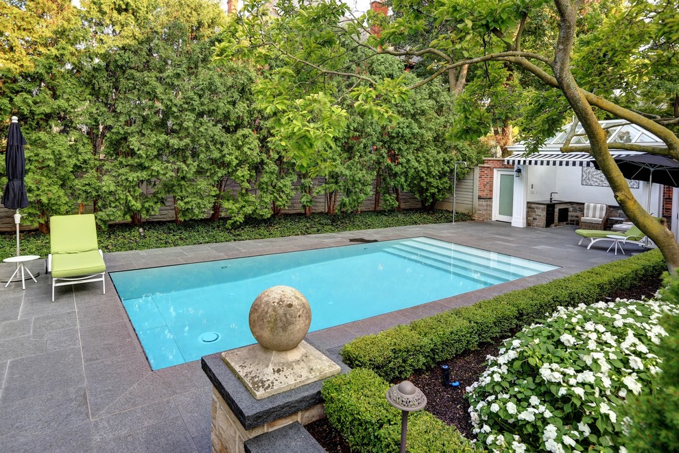 This is an example of a small traditional backyard rectangular infinity pool in Toronto with a pool house and natural stone pavers.