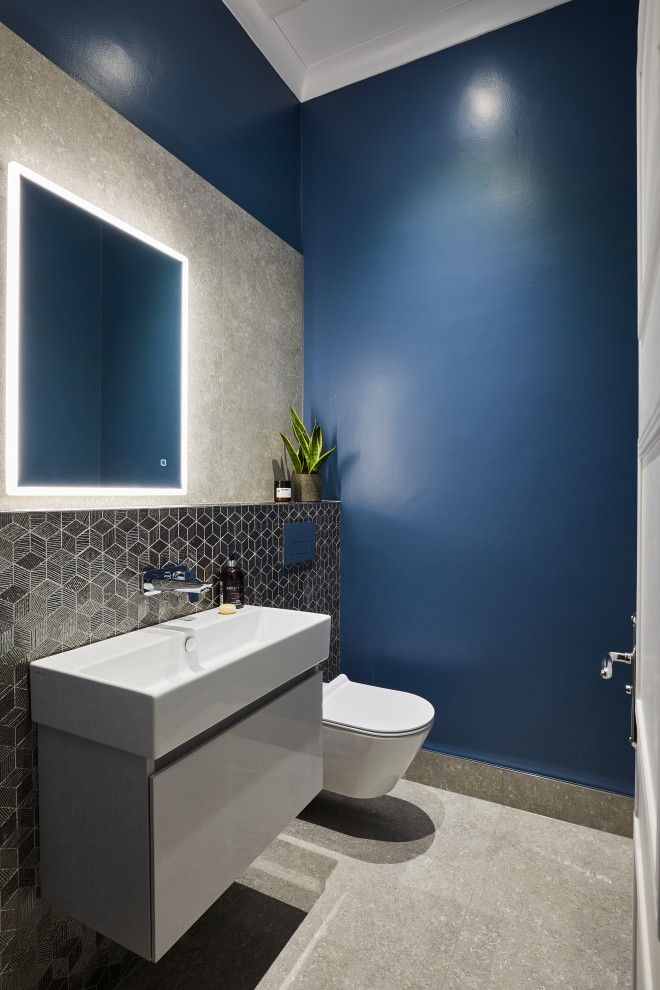 Inredning av ett modernt litet toalett, med vita skåp, en vägghängd toalettstol, blå väggar och ett integrerad handfat