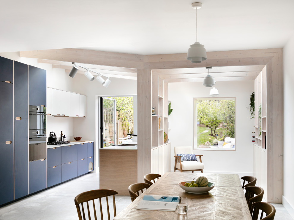 Foto på ett mellanstort skandinaviskt vit kök, med en nedsänkt diskho, släta luckor, blå skåp, bänkskiva i koppar, vitt stänkskydd, svarta vitvaror, klinkergolv i porslin och grått golv