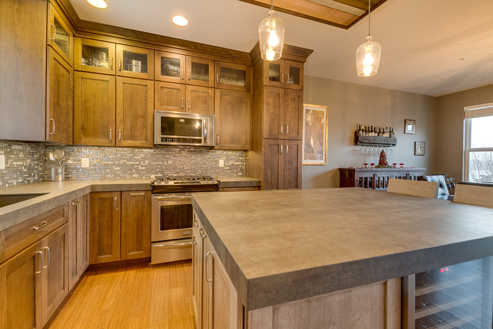 Inspiration for a mid-sized transitional l-shaped bamboo floor open concept kitchen remodel in Seattle with an undermount sink, flat-panel cabinets, brown cabinets, gray backsplash, mosaic tile backsplash, stainless steel appliances and an island