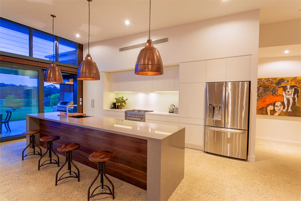 Inspiration for an expansive contemporary galley eat-in kitchen in Brisbane with an undermount sink, flat-panel cabinets, white cabinets, quartz benchtops, white splashback, glass sheet splashback, stainless steel appliances, concrete floors and with island.