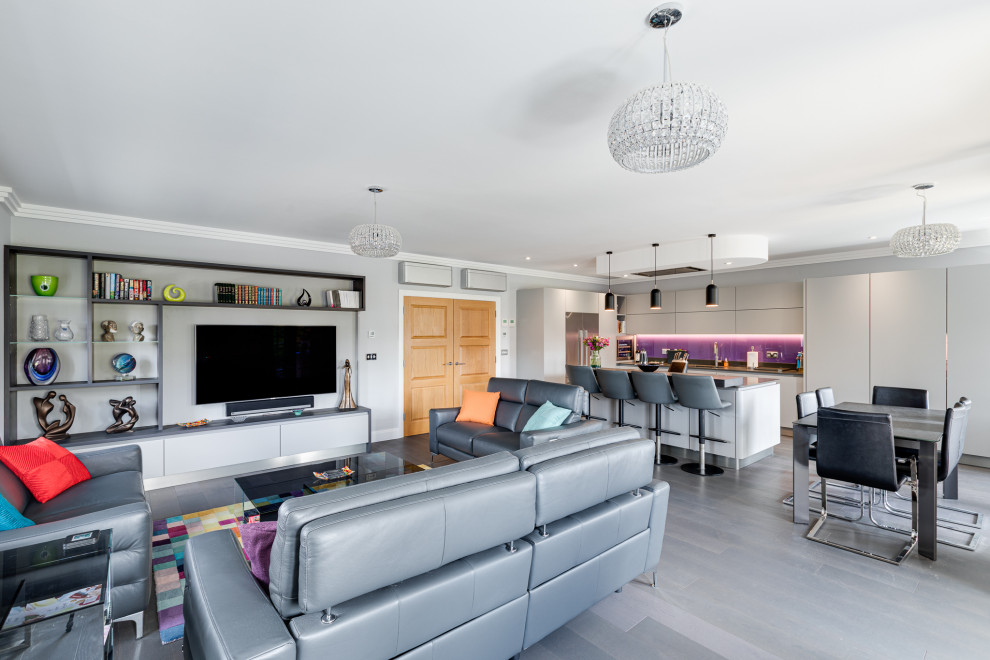 This is an example of a large contemporary u-shaped open plan kitchen in Hertfordshire with flat-panel cabinets, grey cabinets, granite benchtops, pink splashback, glass sheet splashback, panelled appliances, with island and grey benchtop.