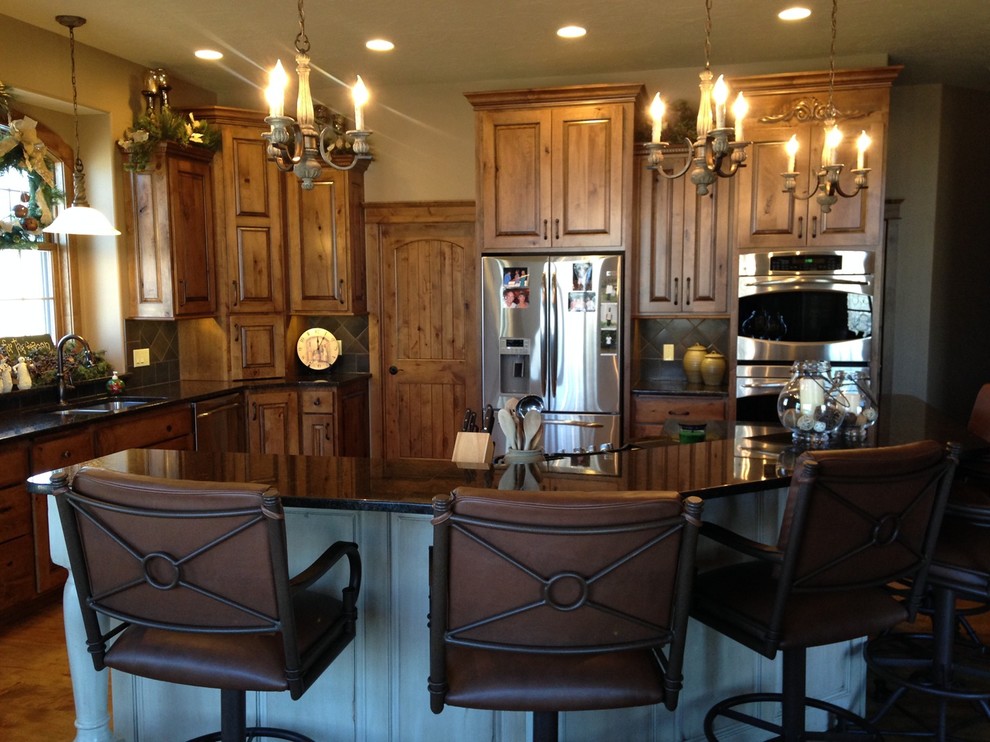 Example of a mid-sized mountain style single-wall medium tone wood floor and brown floor eat-in kitchen design with raised-panel cabinets, light wood cabinets, granite countertops, stainless steel appliances and an island