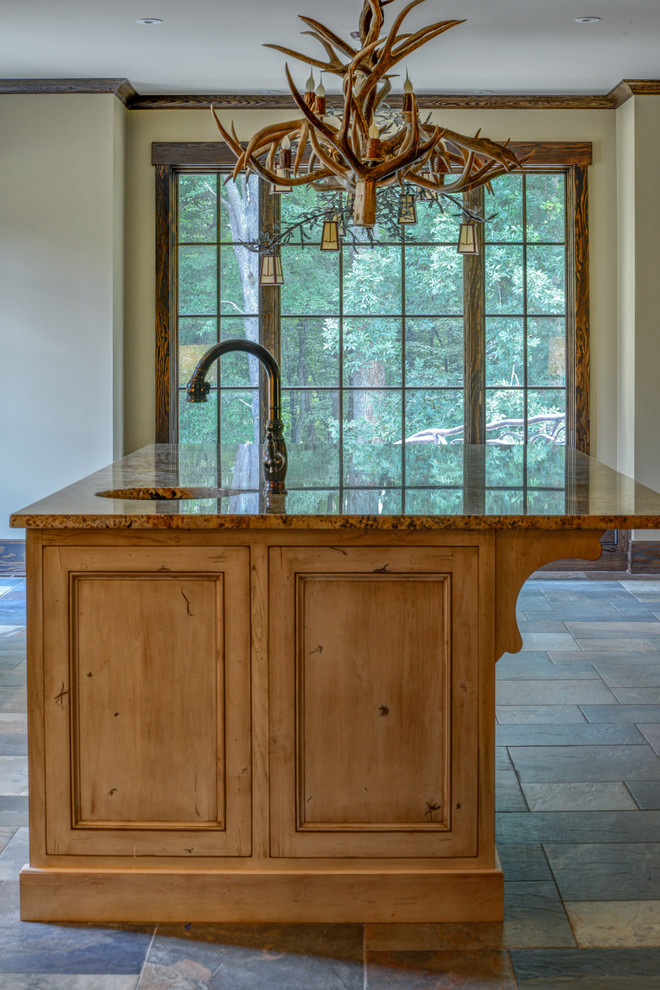 Example of a large mountain style l-shaped slate floor and gray floor enclosed kitchen design with an undermount sink, recessed-panel cabinets, dark wood cabinets, granite countertops, beige backsplash, stone tile backsplash, paneled appliances, a peninsula and brown countertops
