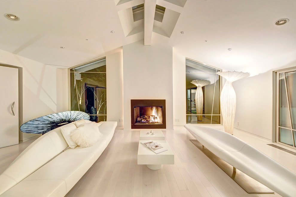 This is an example of a contemporary formal living room in San Francisco with white walls, light hardwood floors, a standard fireplace and a metal fireplace surround.