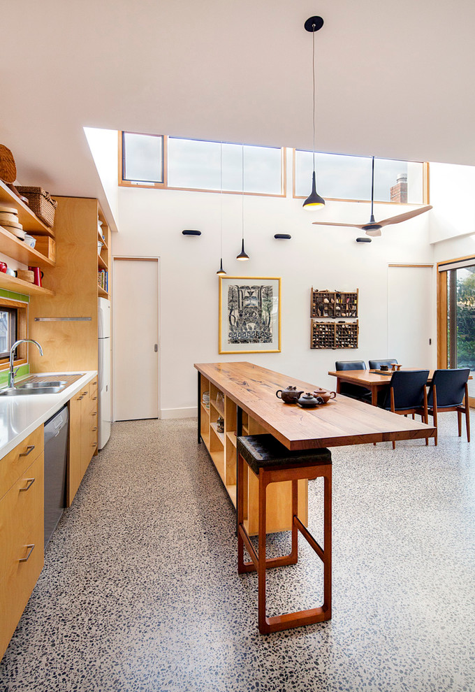 This is an example of a mid-sized contemporary galley open plan kitchen in Melbourne with a drop-in sink, flat-panel cabinets, light wood cabinets, solid surface benchtops, green splashback, ceramic splashback, stainless steel appliances, concrete floors and with island.