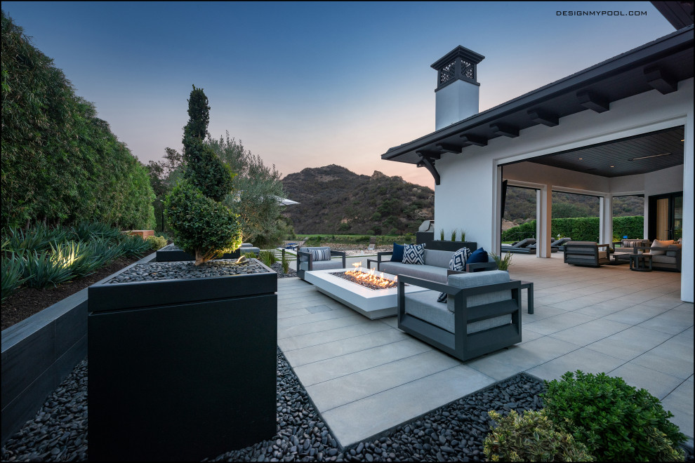 Réalisation d'une terrasse latérale minimaliste avec un foyer extérieur, des pavés en béton et aucune couverture.