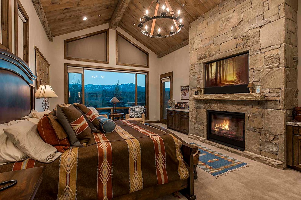 Design ideas for a country master bedroom in Salt Lake City with carpet, a standard fireplace, a stone fireplace surround and grey walls.