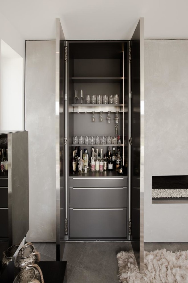This is an example of a mid-sized contemporary single-wall home bar in Berlin with flat-panel cabinets, grey cabinets, grey splashback and grey floor.
