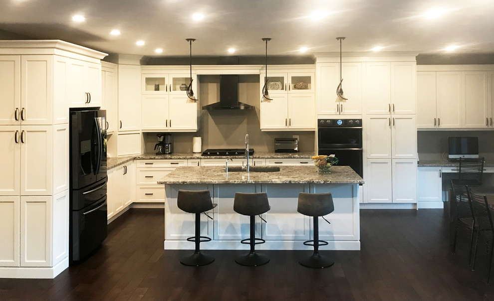 Example of a transitional l-shaped eat-in kitchen design with shaker cabinets, granite countertops and an island