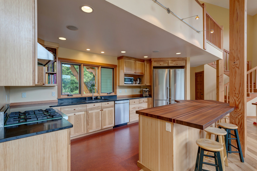 Inspiration for a mid-sized transitional u-shaped laminate floor and brown floor open concept kitchen remodel in Seattle with an undermount sink, recessed-panel cabinets, light wood cabinets, wood countertops, stainless steel appliances and an island