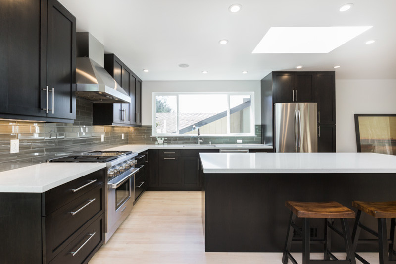 Design ideas for a large contemporary l-shaped eat-in kitchen in San Francisco with an integrated sink, quartz benchtops, stainless steel appliances, shaker cabinets, black cabinets, light hardwood floors and with island.