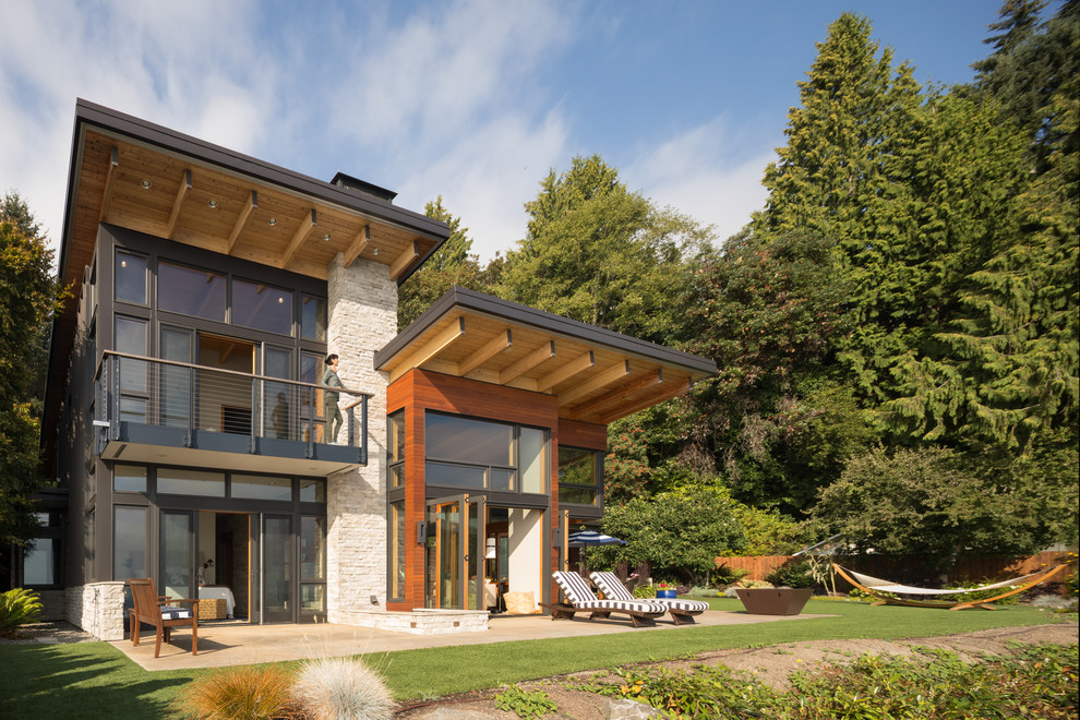 Mid-sized contemporary two-storey beige house exterior in Seattle with stone veneer, a shed roof and a metal roof.
