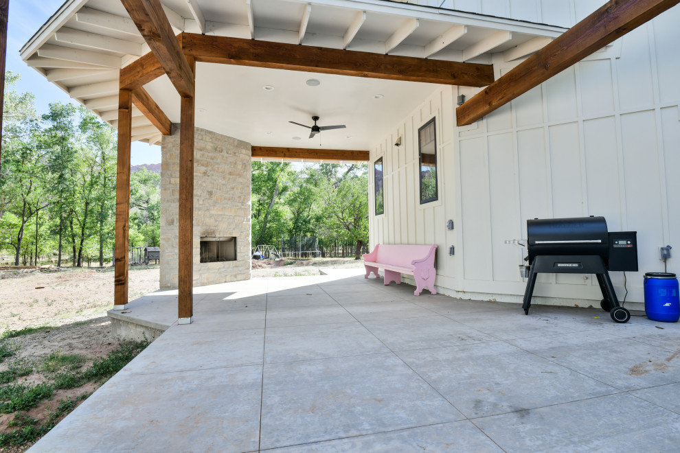 Esempio di un grande patio o portico american style dietro casa con un caminetto, pavimentazioni in cemento e un tetto a sbalzo