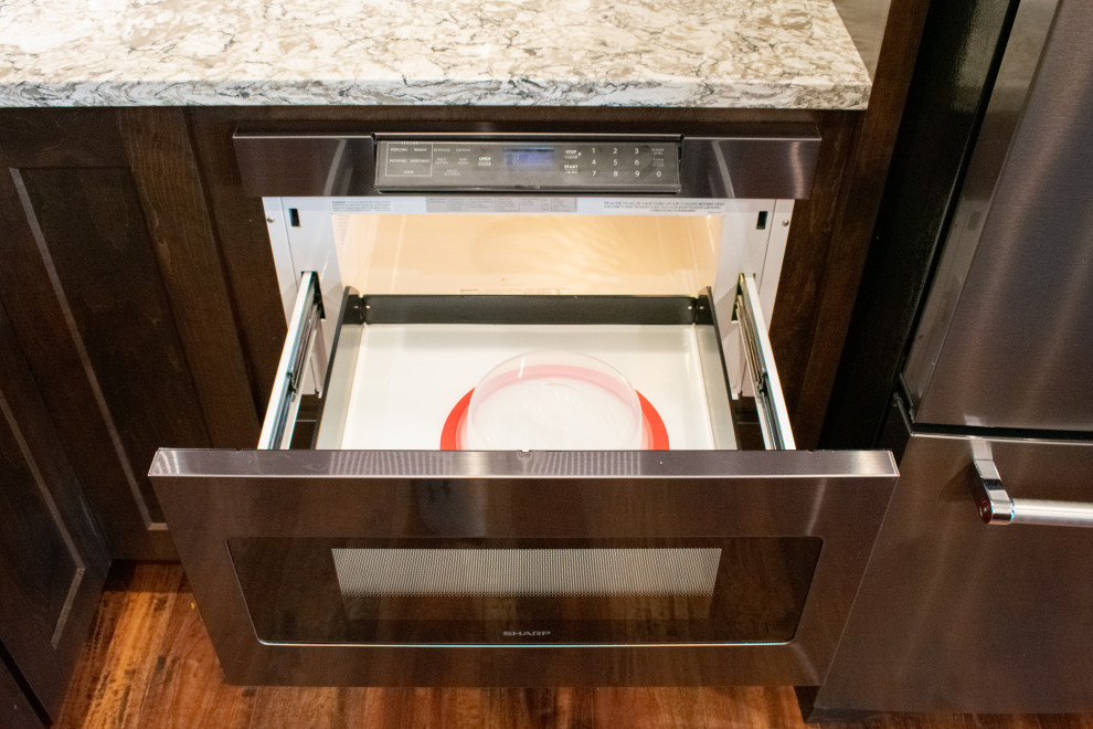 Inspiration for a large transitional l-shaped vinyl floor, brown floor and vaulted ceiling eat-in kitchen remodel with an undermount sink, flat-panel cabinets, medium tone wood cabinets, quartz countertops, gray backsplash, ceramic backsplash, black appliances, an island and beige countertops