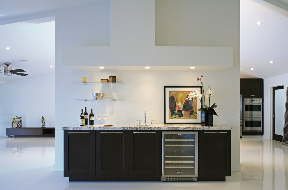 This is an example of a large modern single-wall wet bar in Other with dark wood cabinets, white splashback, an undermount sink, granite benchtops, concrete floors, shaker cabinets and grey benchtop.