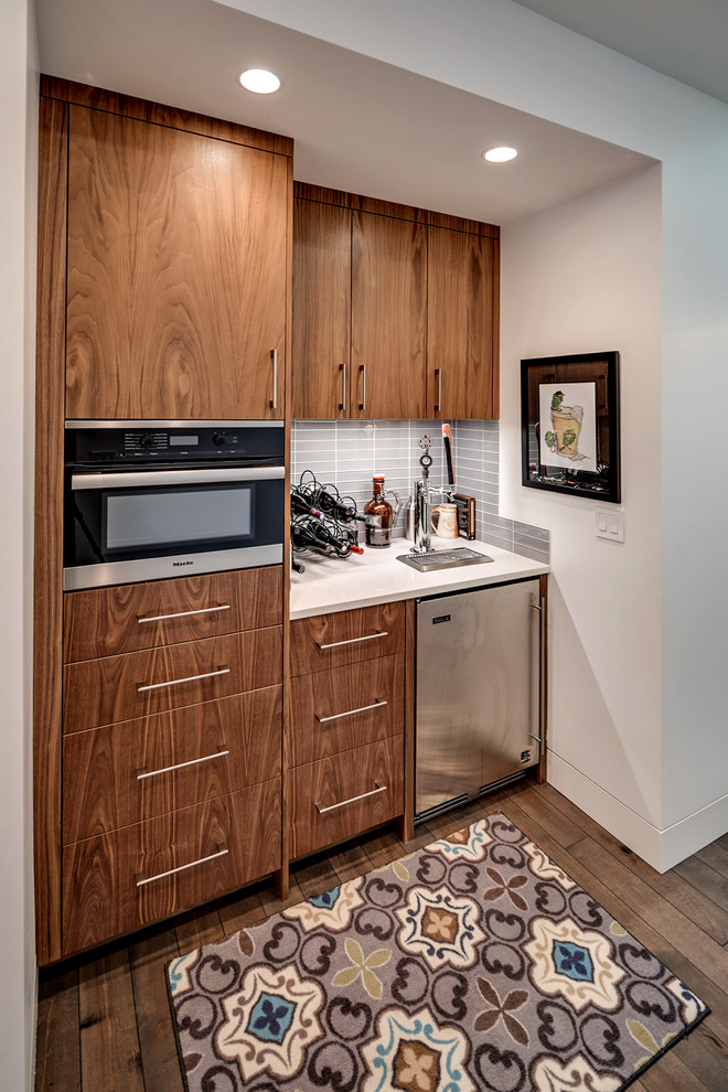 Mid-sized arts and crafts l-shaped eat-in kitchen in Portland with flat-panel cabinets, dark wood cabinets, solid surface benchtops, grey splashback, porcelain splashback, stainless steel appliances, dark hardwood floors and brown floor.