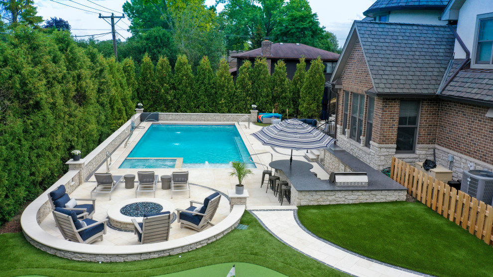 Ejemplo de piscina alargada tradicional de tamaño medio rectangular en patio trasero con privacidad y adoquines de piedra natural