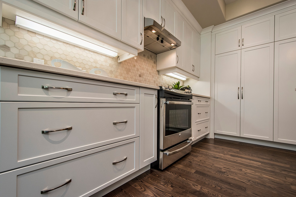 Inspiration for a large transitional l-shaped dark wood floor open concept kitchen remodel with a double-bowl sink, shaker cabinets, white cabinets, quartzite countertops, beige backsplash, porcelain backsplash, stainless steel appliances and an island