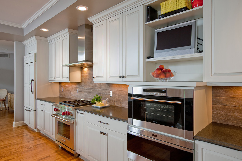 Design ideas for a mid-sized transitional galley open plan kitchen in Minneapolis with an undermount sink, raised-panel cabinets, white cabinets, granite benchtops, brown splashback, porcelain splashback, stainless steel appliances, light hardwood floors and with island.