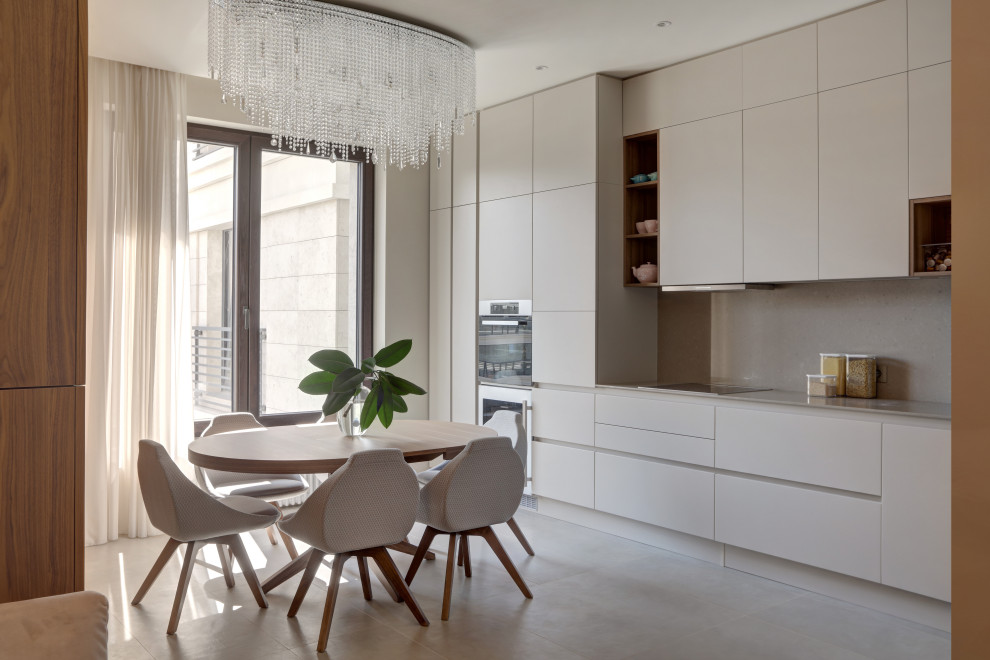 This is an example of a contemporary l-shaped eat-in kitchen in Saint Petersburg with an undermount sink, flat-panel cabinets, beige cabinets, solid surface benchtops, beige splashback, engineered quartz splashback, stainless steel appliances, porcelain floors, beige floor and beige benchtop.