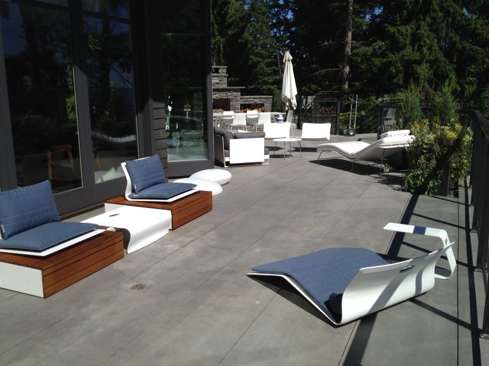 This is an example of a large contemporary backyard patio in Vancouver with a fire feature, concrete slab and no cover.