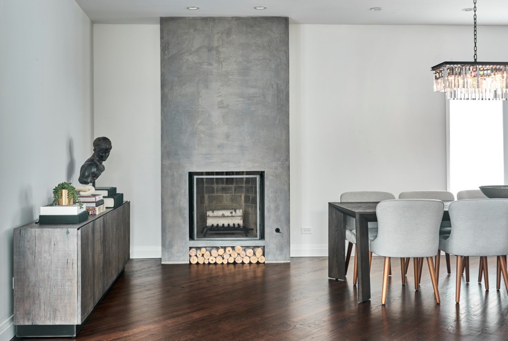 This is an example of a large classic kitchen/dining room in Chicago with grey walls, dark hardwood flooring, a standard fireplace, a concrete fireplace surround and brown floors.