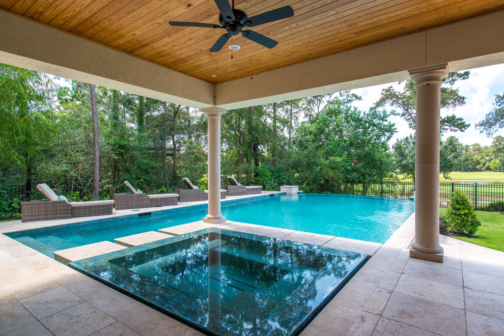 Design ideas for a large transitional backyard rectangular infinity pool in Houston with a hot tub and natural stone pavers.