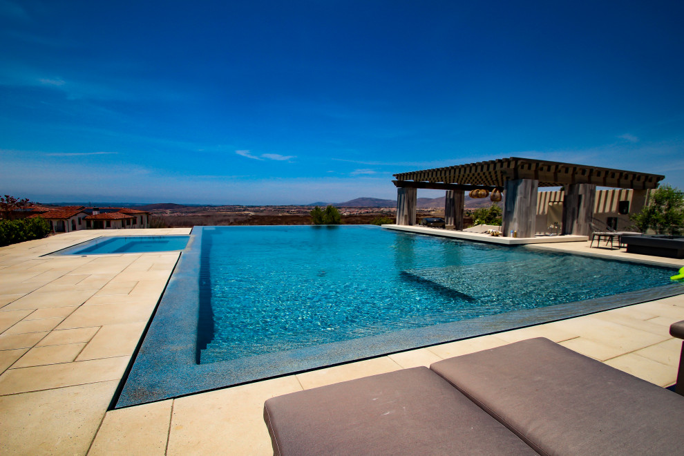 This is an example of a large contemporary backyard rectangular infinity pool in San Diego with with a pool and tile.