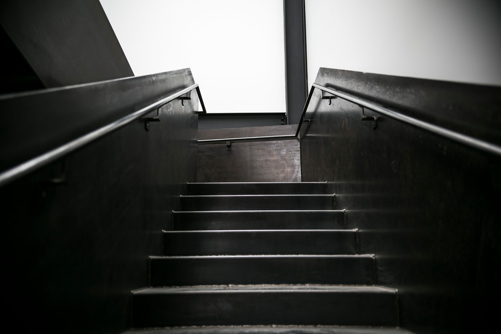 Large industrial metal u-shaped staircase in Seattle with metal risers and metal railing.