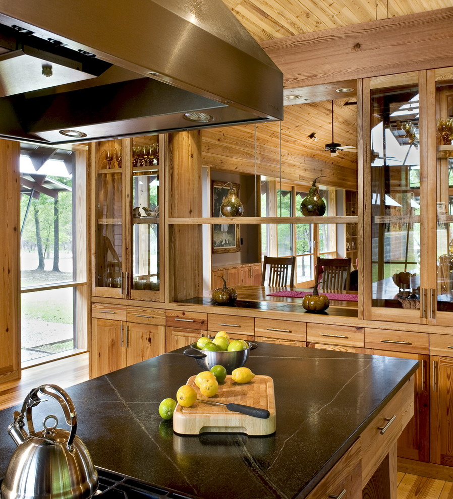 Photo of a country kitchen in Charleston with glass-front cabinets, soapstone benchtops and medium wood cabinets.