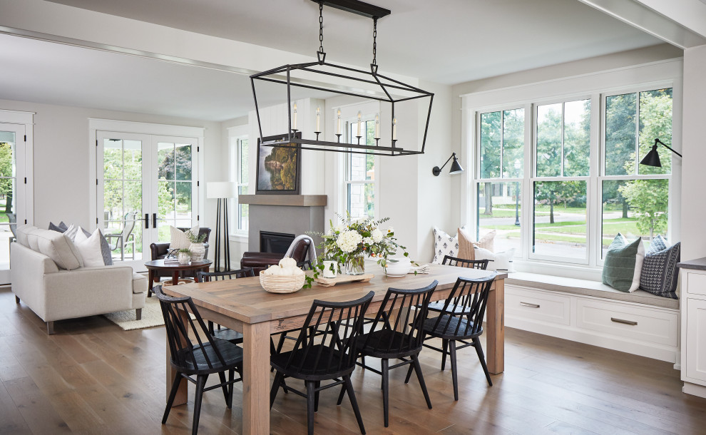 Mid-sized country open plan dining in Grand Rapids with white walls, medium hardwood floors, a standard fireplace and a concrete fireplace surround.