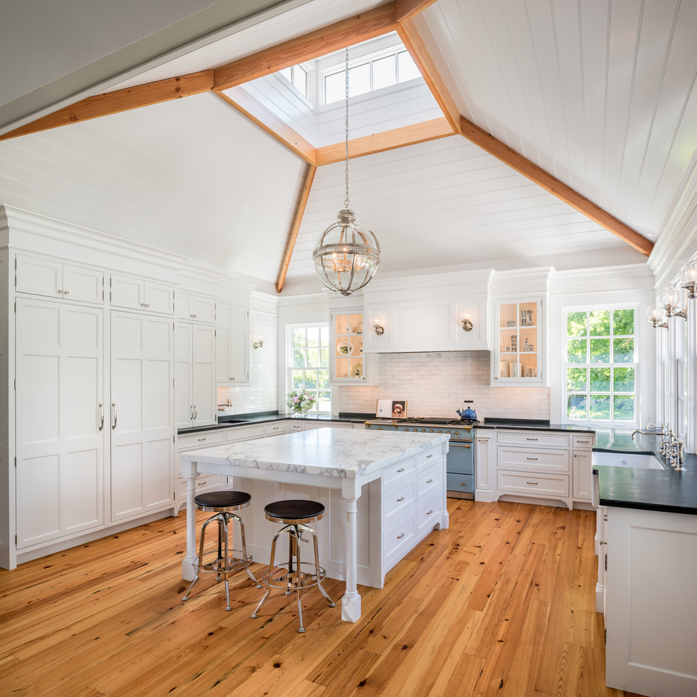 Inspiration for a traditional u-shaped kitchen in Philadelphia with a farmhouse sink, white cabinets, white splashback, coloured appliances, medium hardwood floors, with island and shaker cabinets.