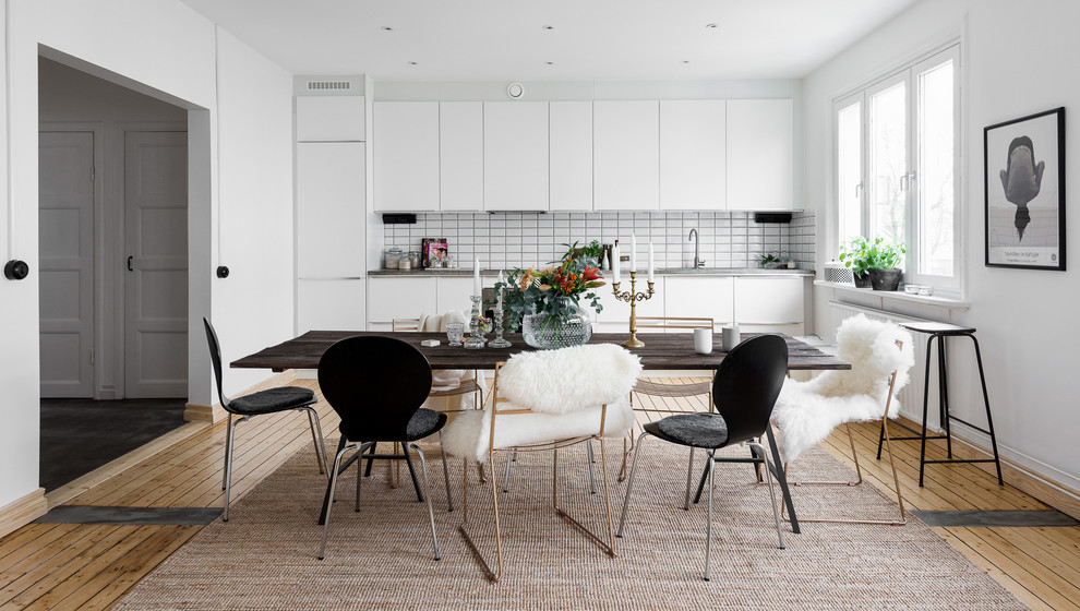 Photo of a large scandinavian single-wall eat-in kitchen in Gothenburg with a single-bowl sink, flat-panel cabinets, white cabinets, concrete benchtops, white splashback, ceramic splashback, white appliances, light hardwood floors and no island.