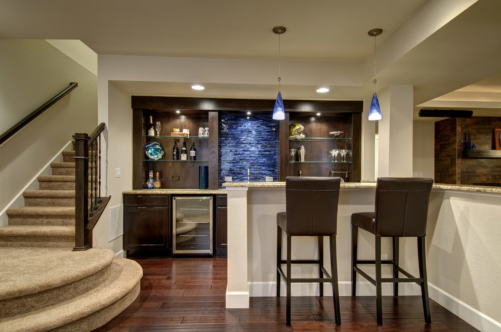 Seated home bar - large transitional u-shaped dark wood floor and brown floor seated home bar idea in Denver with an undermount sink, raised-panel cabinets, dark wood cabinets, granite countertops, blue backsplash, glass tile backsplash and beige countertops