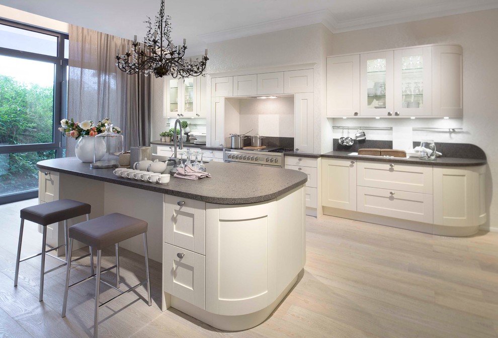 This is an example of an expansive contemporary eat-in kitchen in Berlin with recessed-panel cabinets, white cabinets, with island, an undermount sink, white splashback, stainless steel appliances and light hardwood floors.