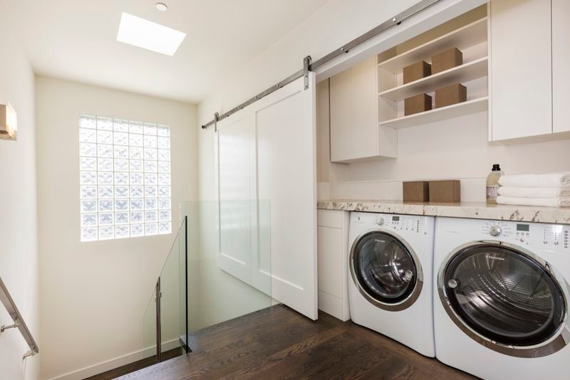 This is an example of a small arts and crafts single-wall laundry cupboard in San Francisco with white cabinets, granite benchtops, a side-by-side washer and dryer, flat-panel cabinets, beige walls, dark hardwood floors and brown floor.