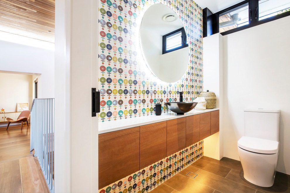 Contemporary powder room in Sydney with flat-panel cabinets, medium wood cabinets, white walls, a vessel sink, engineered quartz benchtops, brown floor, white benchtops, a floating vanity and wallpaper.