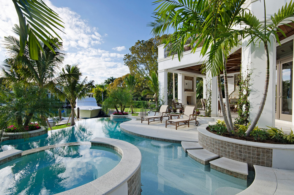 Photo of a tropical backyard custom-shaped infinity pool in Miami.